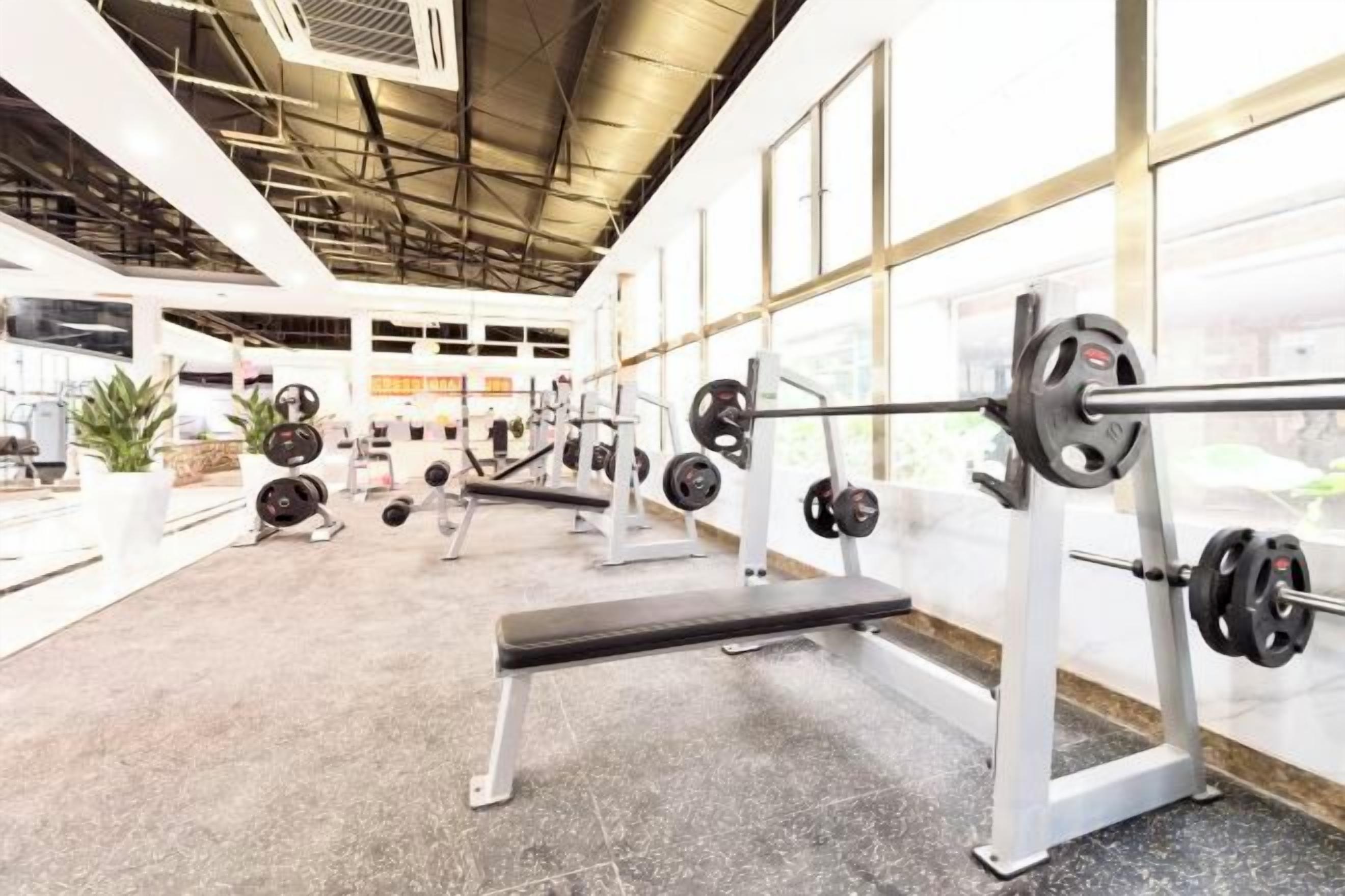 A gym with weightlifting equipment, benches, and a large window.