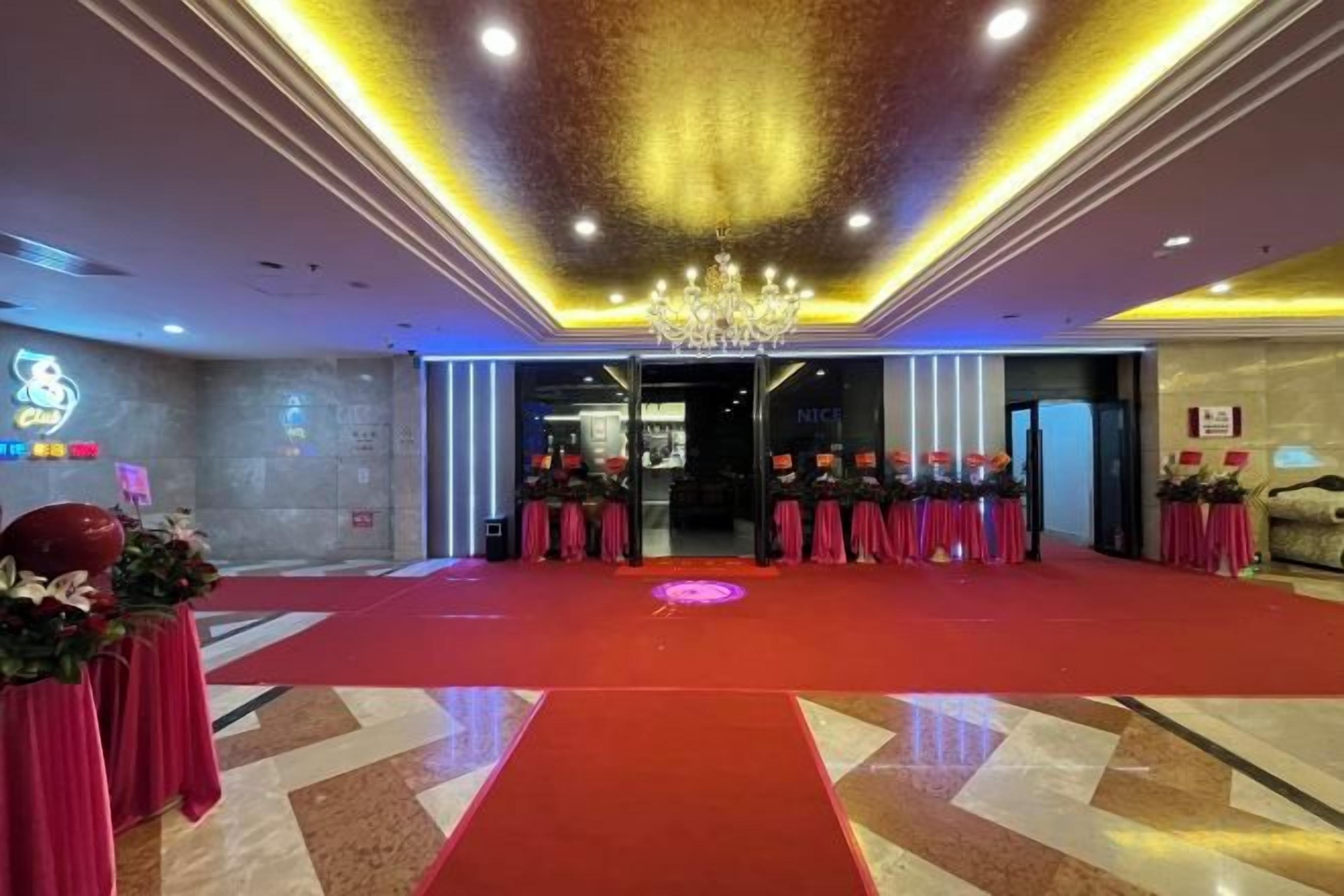 Eine Hotelhalle mit rotem Teppich, einem Chandelier und einem Empfangstresen.