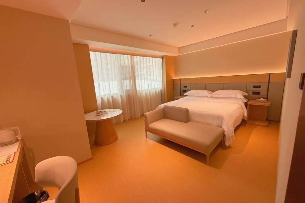 A hotel room with a bed, bedside table, chair, and a small round table.