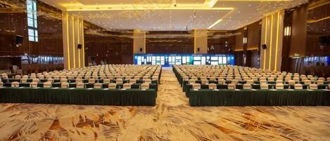 A large conference room with rows of tables and chairs, a patterned carpet, and a modern ceiling design.