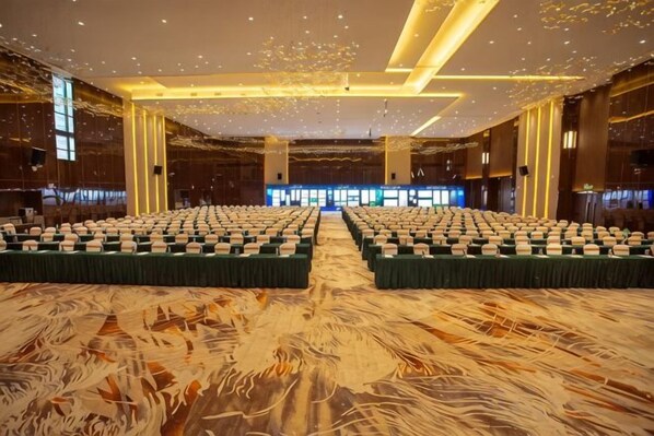 A large conference room with rows of tables and chairs, a patterned carpet, and a modern ceiling design. - Foshan Sanshui ShiHuang Garden Hotel (Foshan)