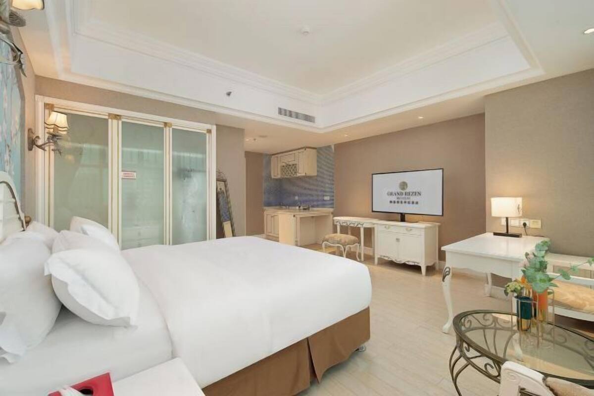 A hotel room with a large bed, a desk, a chair, and a television.