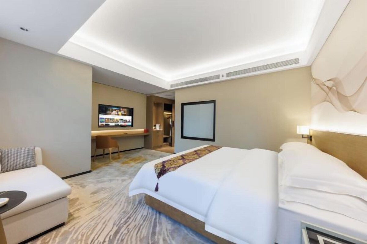 Habitació d'hotel amb llit, escriptori, cadira i televisió.