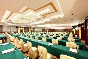 Un salón de conferencias con mesas, sillas y una araña.