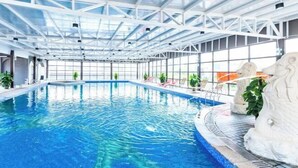 An indoor swimming pool with clear blue water, surrounded by a white metal roof structure and large windows. - Foshan Sanshui ShiHuang Garden Hotel (Foshan)