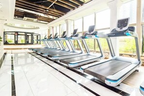 A row of treadmills in a gym with a modern design, large windows, and a clean, tiled floor. - Foshan Sanshui ShiHuang Garden Hotel (Foshan)