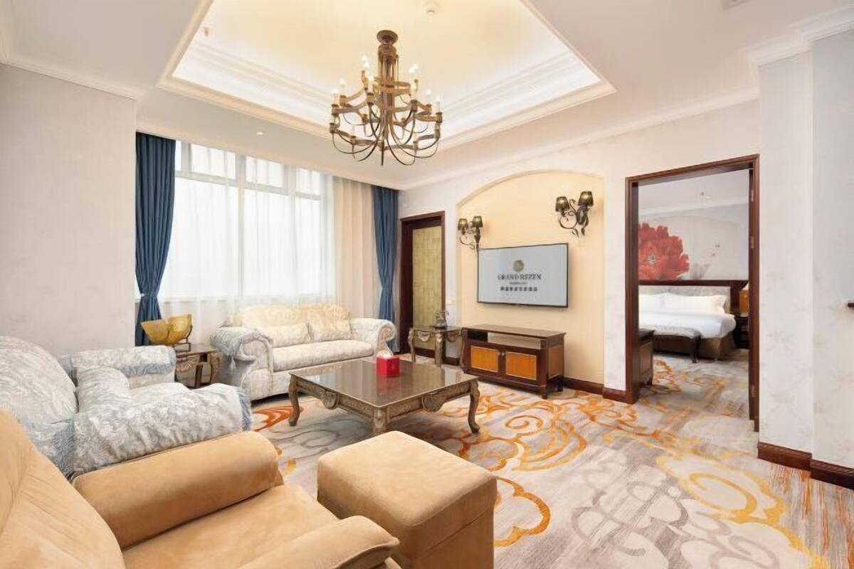 A hotel room with a sofa, armchair, coffee table, and a bed.