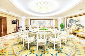 A round dining table with chairs, a chandelier, and a floral carpet. - Foshan Sanshui ShiHuang Garden Hotel (Foshan)