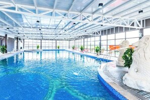 An indoor swimming pool with clear blue water, surrounded by white structural beams and glass walls. - Foshan Sanshui ShiHuang Garden Hotel (Foshan)