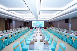 A conference room with rows of tables and chairs, a large screen at the front, and a stage. - Foshan Sanshui ShiHuang Garden Hotel (Foshan)