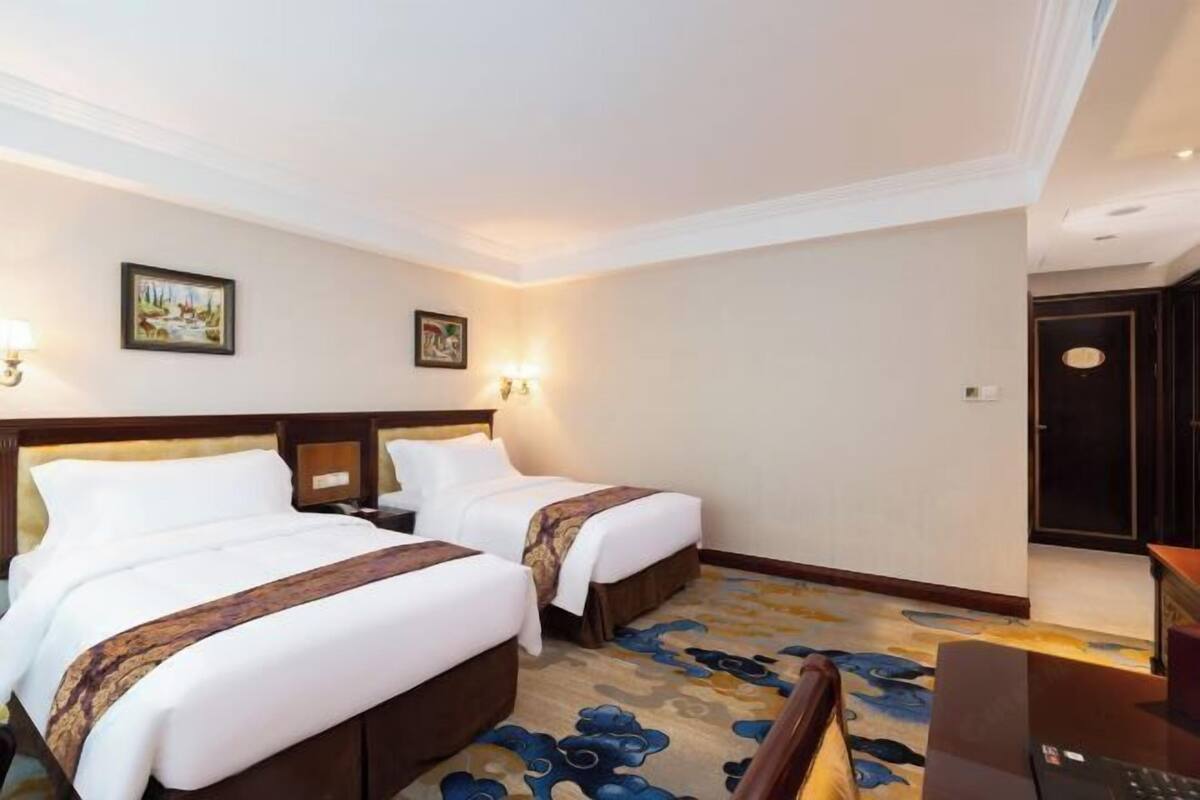 A hotel room with two beds, a desk, and a chair.