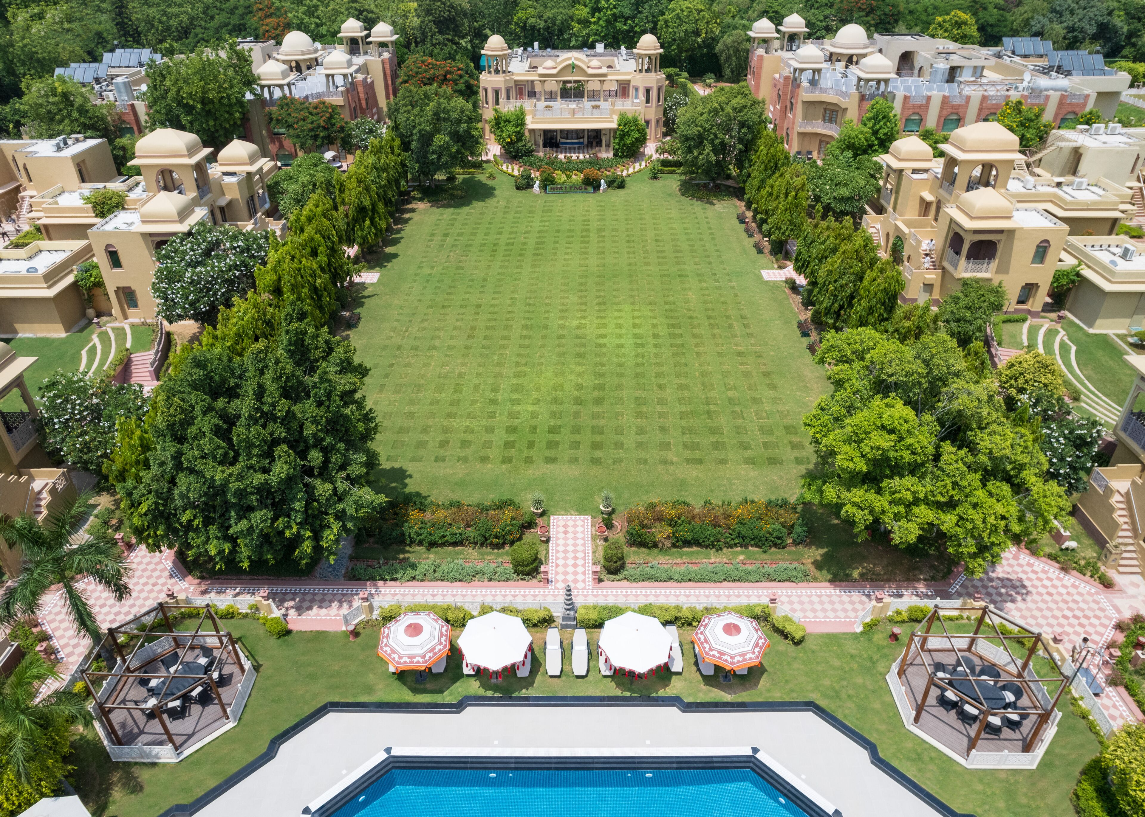 An aerial view of a resort with a central lawn, multiple buildings with domed roofs, and a swimming pool.