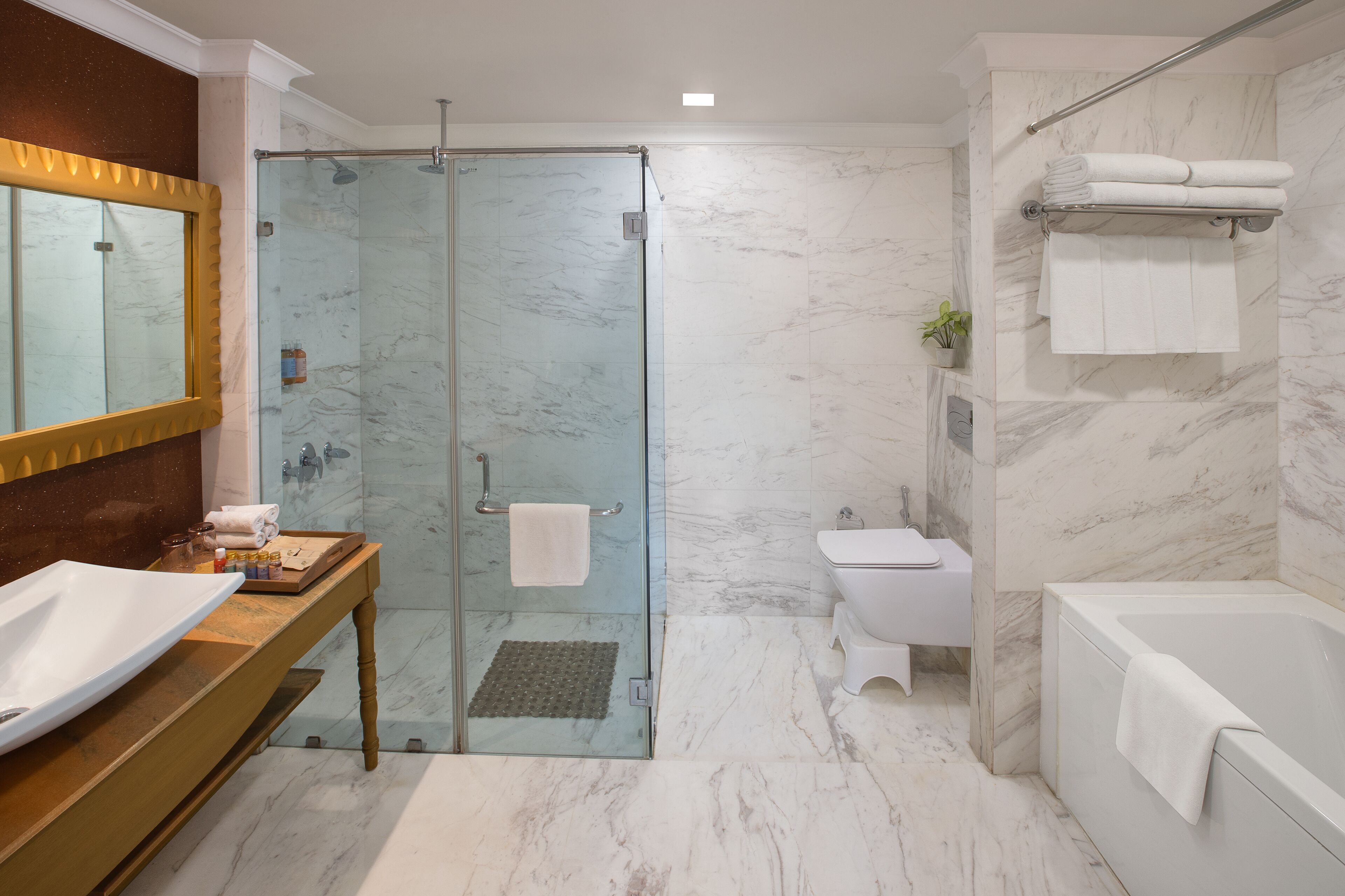 A modern bathroom with a glass-enclosed shower, a wooden vanity with a sink, a toilet, and a bathtub.