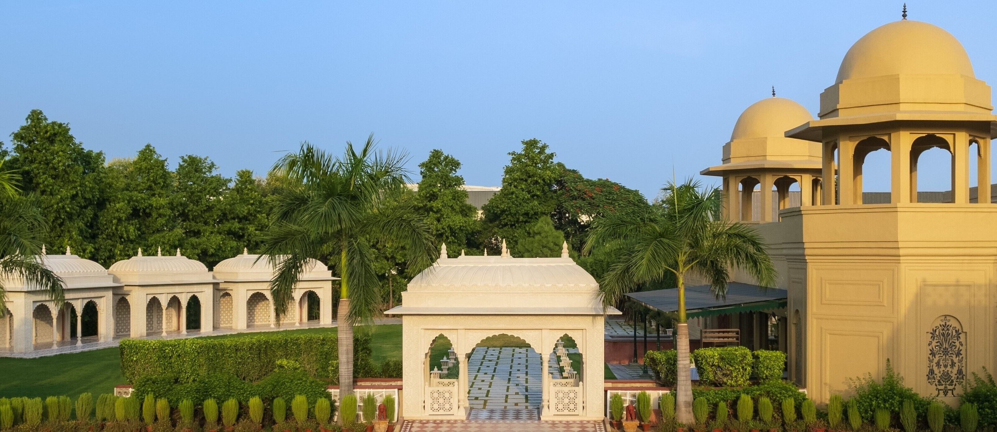 A traditional building with domed structures and arched gateways, surrounded by well-maintained greenery.