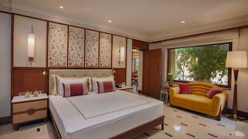 A spacious bedroom with a large bed, a sofa, and a view of greenery outside.
