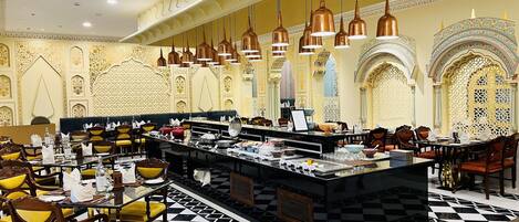 A restaurant with a central bar area, multiple seating arrangements, and ornate wall decorations.