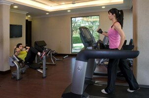 A gym with treadmills, weight machines, and a TV on the wall.
