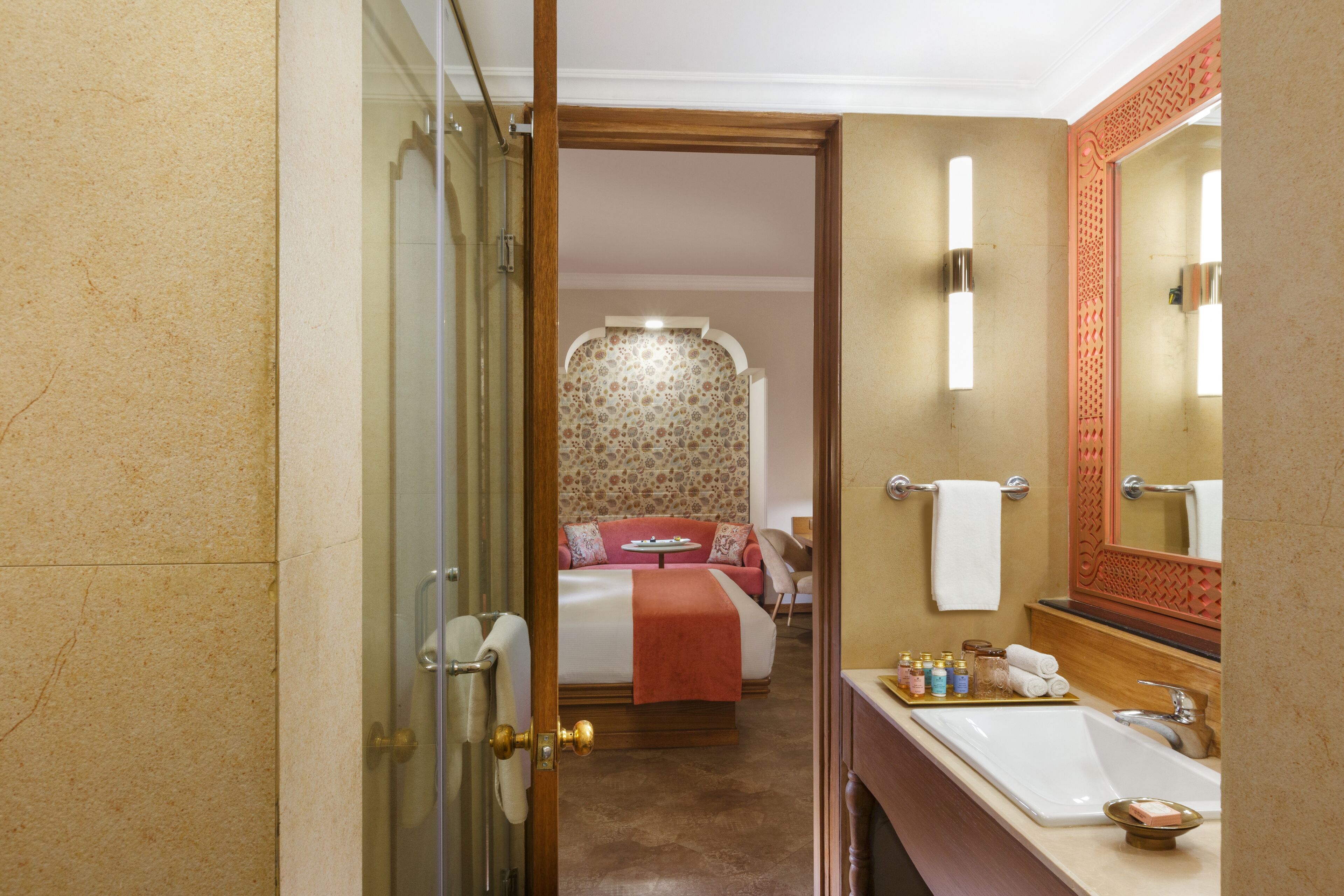 Un baño de hotel con un espejo grande, un lavamanos y una zona de ducha.
