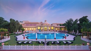 A large hotel with a central swimming pool, multiple dining areas, and lush landscaping.