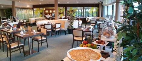 Un restaurante moderno con varias áreas de comedor, una barra central y diversas opciones de comida y bebida expuestas sobre las mesas.