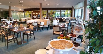Un restaurante moderno con varias áreas de comedor, una barra central y diversas opciones de comida y bebida expuestas sobre las mesas.