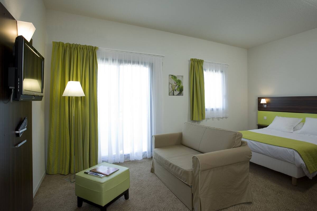 Una habitación de hotel con una cama, un sofá, una mesita y un televisor.