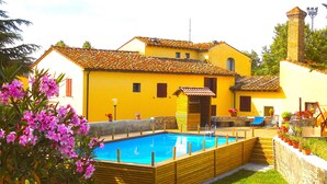 A yellow building with a tiled roof, a swimming pool, and a staircase leading to a door. - Il Molino del Ponte (Montespertoli)
