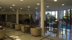 A spacious lobby with a glass partition, comfortable seating, and large windows offering a view of the outdoors. - Helios Spa (Golden Sands)