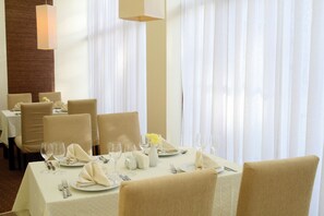 Un comedor con una mesa dispuesta para cuatro personas, incluyendo copas de vino, platos y cubiertos.