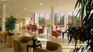 A spacious lobby with comfortable seating, large windows, and potted plants. - Helios Spa (Golden Sands)