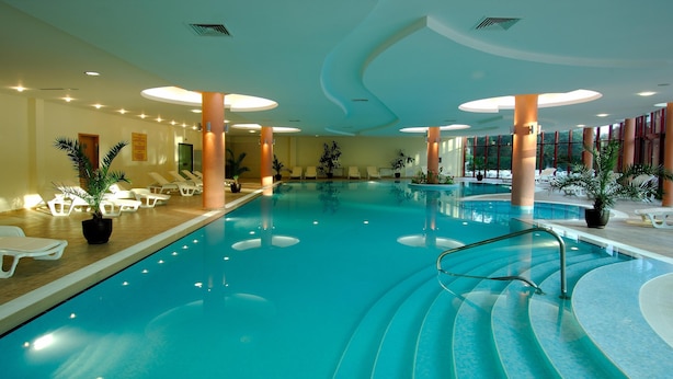 An indoor swimming pool with lounge chairs and potted plants. - Helios Spa (Golden Sands)
