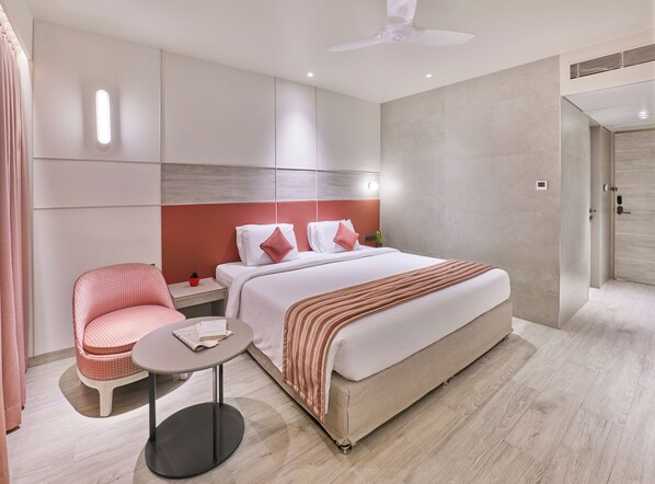 Una habitación de hotel moderna con una cama, un rincón de descanso con una mesa y un ventilador de techo.