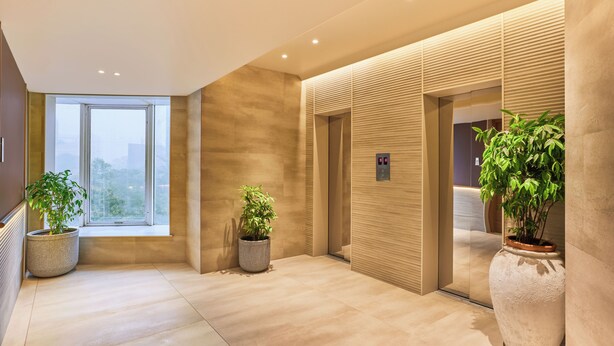 Un hall d’hôtel moderne doté d’une grande fenêtre, de plantes en pot et d’un aménagement épuré et minimaliste.