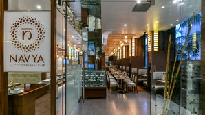 Un intérieur moderne comprenant un comptoir d’accueil, des vitrines et un grand espace de restauration avec des tables et des chaises.