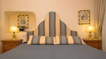 A neatly made bed with a striped headboard, two bedside tables with lamps, and framed pictures on the walls.
