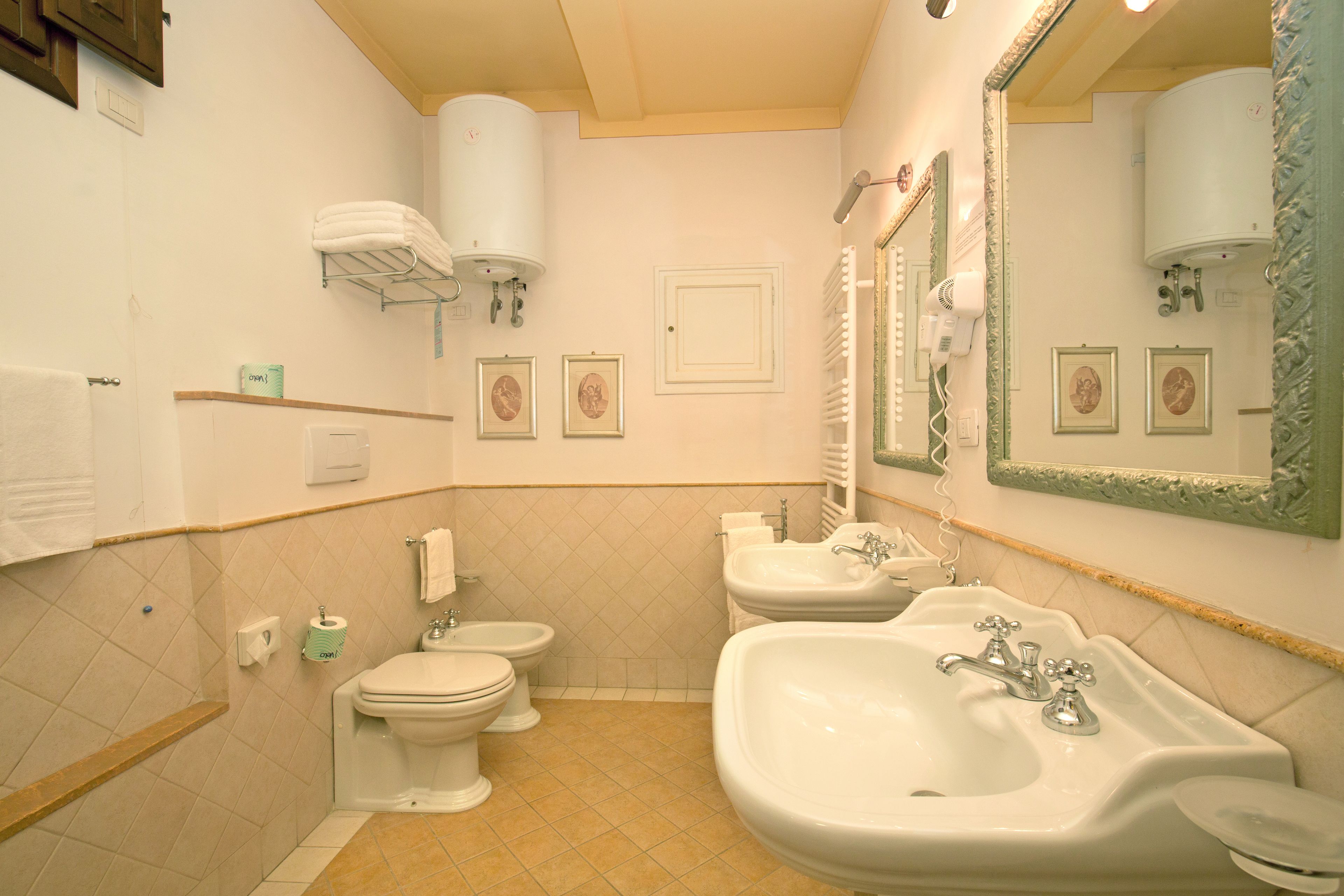 A bathroom with a toilet, bidet, sink, and mirror.
