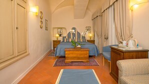 Ein Schlafzimmer mit Bett, Nachttischen, einem Sessel, einer Couch, einer Lampe und einer Wandleuchte.