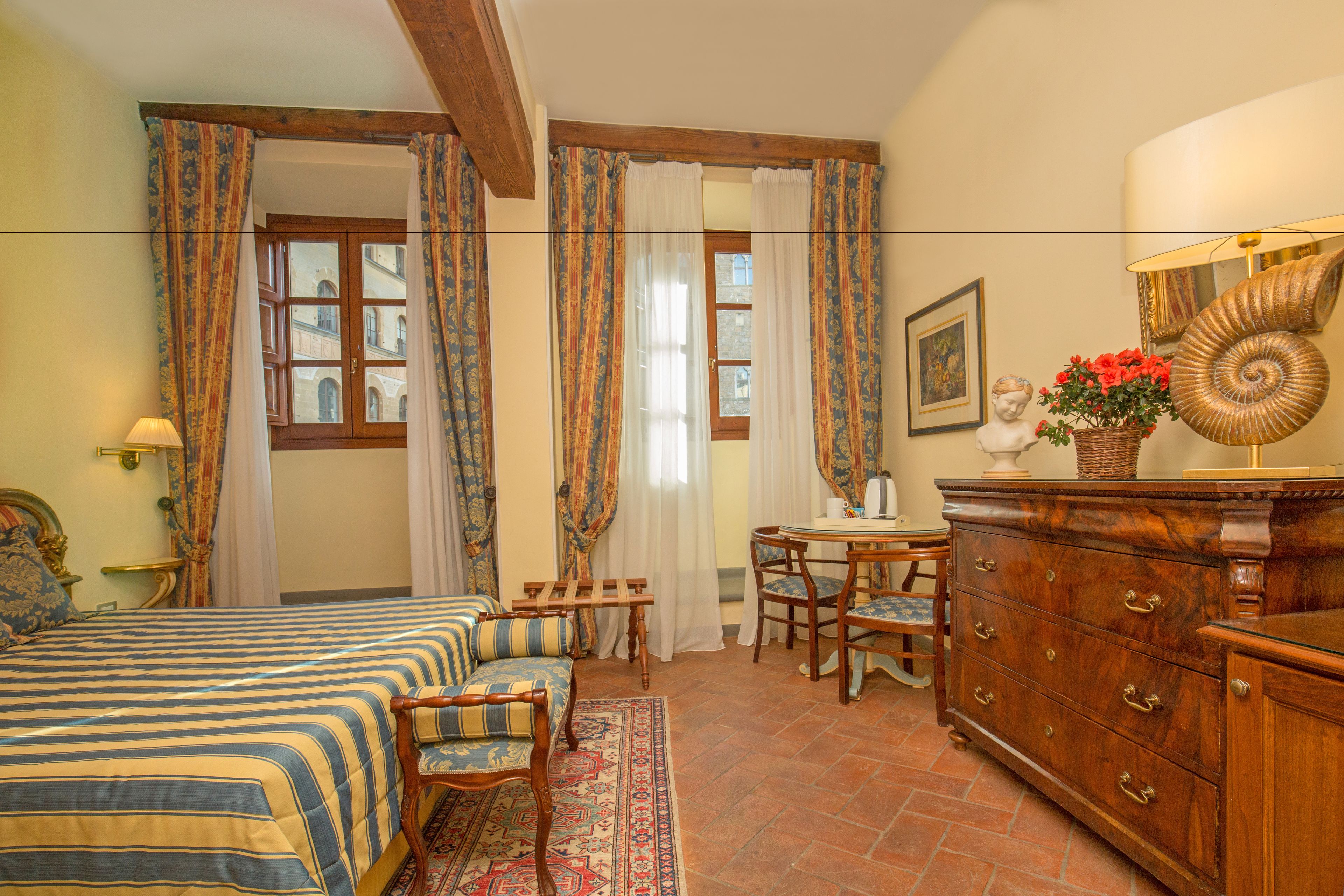 A bedroom with a bed, a sofa, a dresser, and a desk with chairs.
