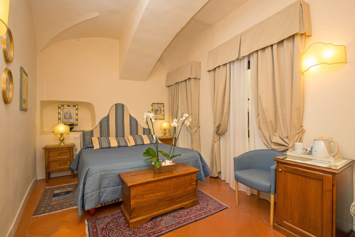 Une chambre d’hôtel comprenant un lit, des tables de chevet, une chaise, un bureau et une lampe.