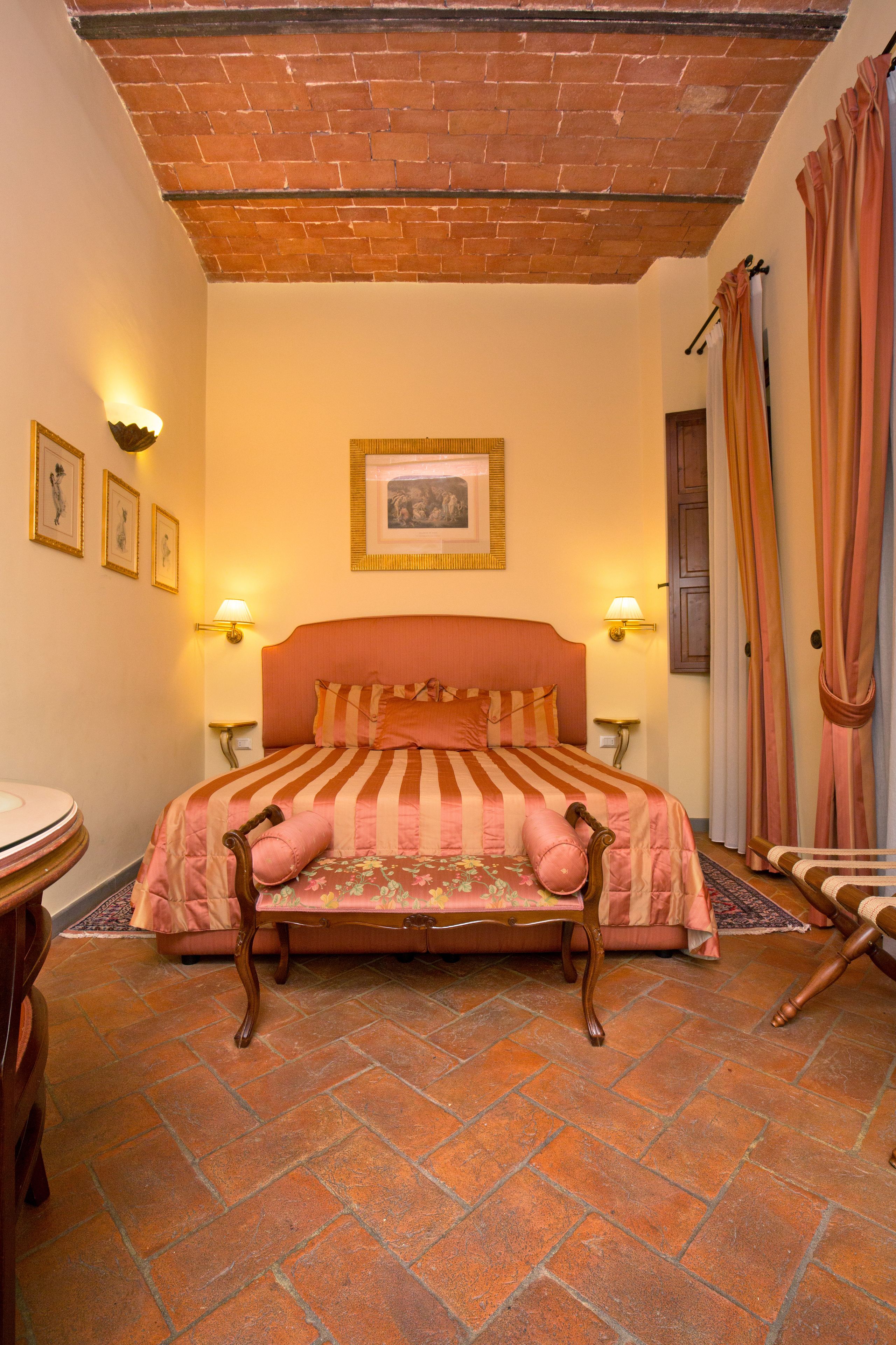 Ein Schlafzimmer mit Ziegeldecke, einem großen Bett mit gestreifter Bettwäsche, zwei Nachttischlampen und einem gerahmten Bild an der Wand.