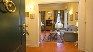 Ein Wohnzimmer mit einer Couch, einem Couchtisch und einem Fernseher. Eine Tür mit Messingklinke und Schlüssel ist angebracht.