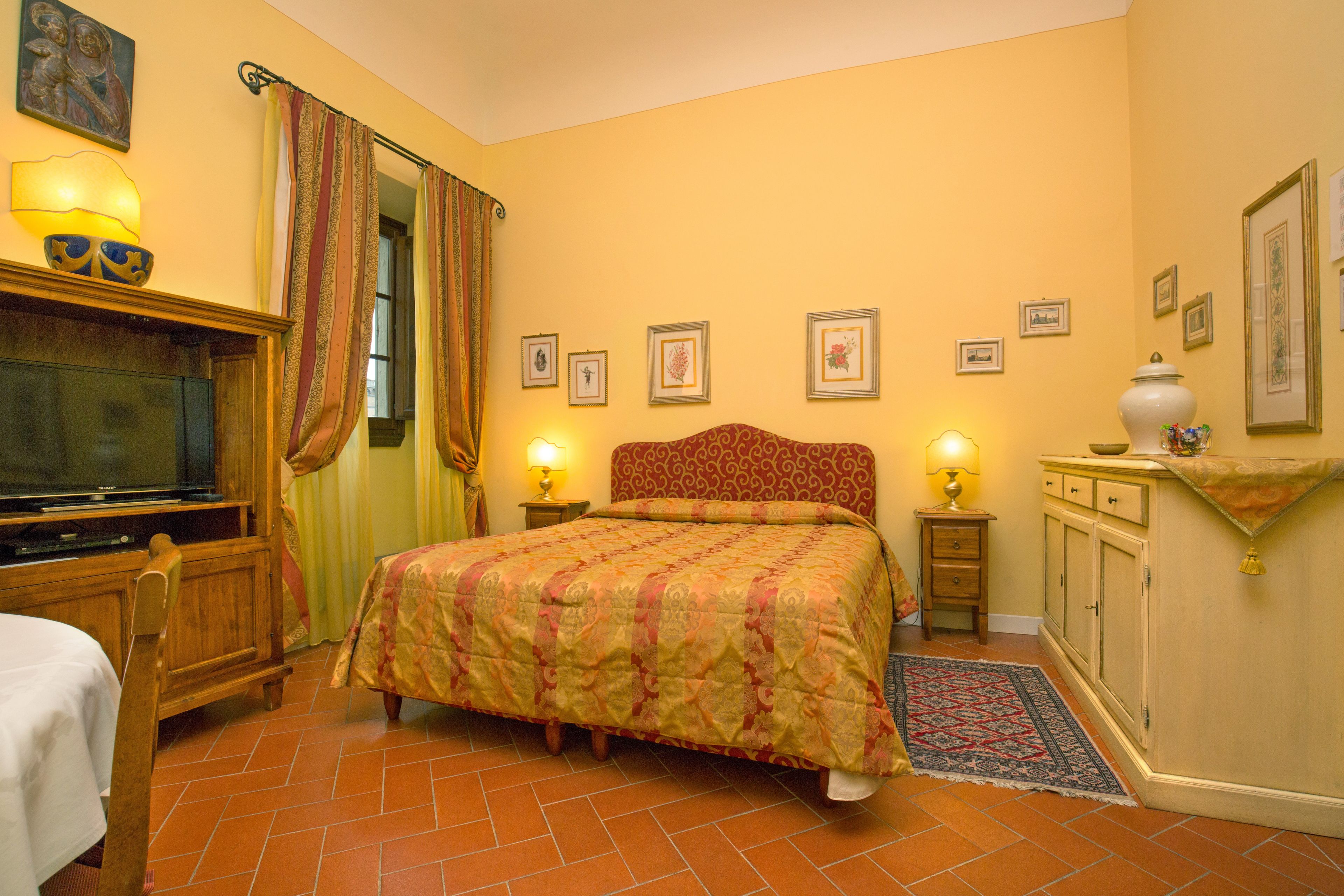 A bedroom with a bed, a television, a lamp, and a cabinet.