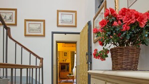Ein Flur mit einer Treppe, einem Korbwesen mit roten Blumen und einem cremefarbenen Schrank.