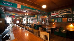 A bar area with wooden bar counter and seating. - Rogues' Harbor Inn (Lansing)