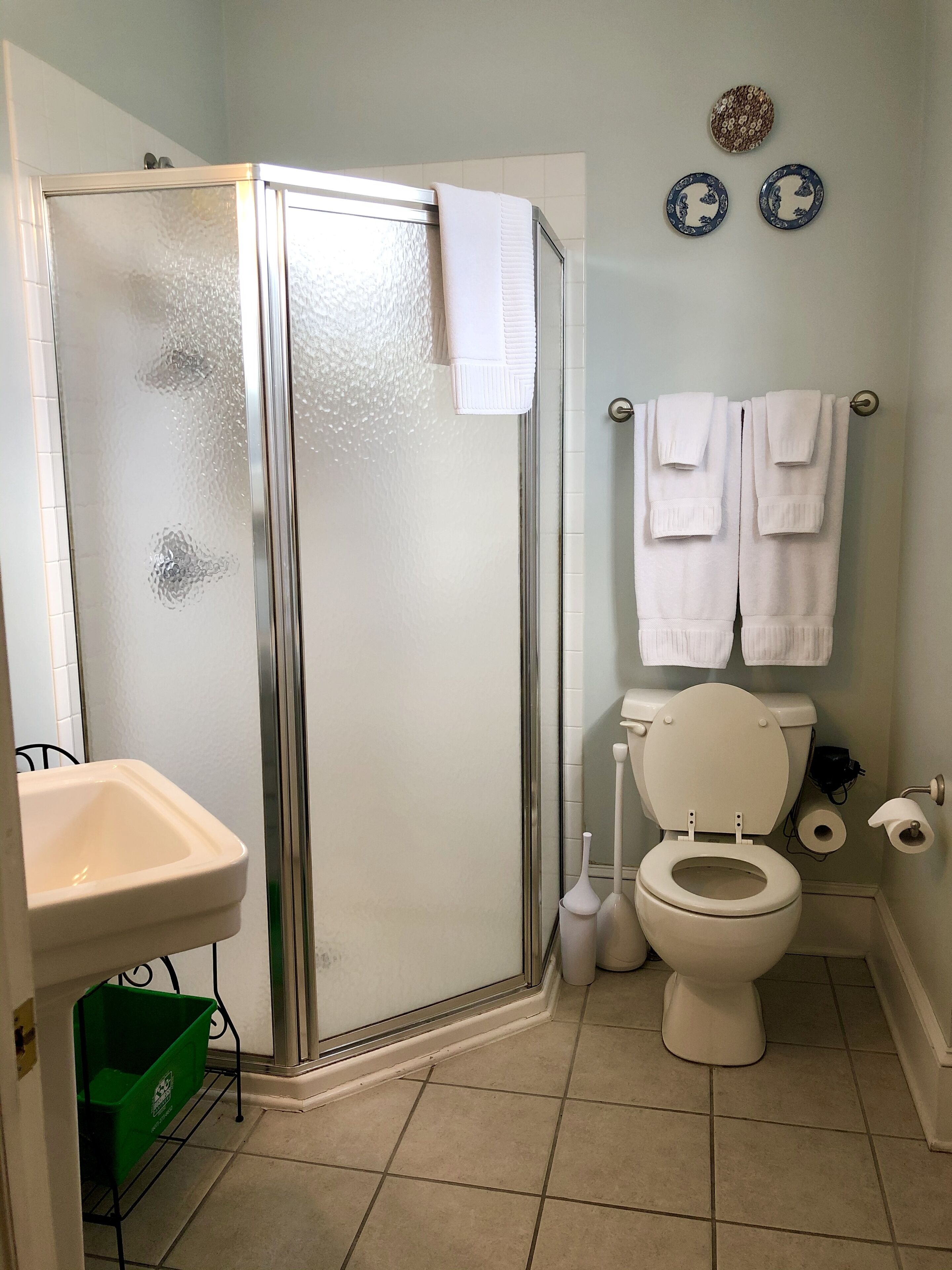 A bathroom with a shower enclosure, toilet, sink, and towel rack.