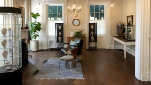 A spacious room with wooden flooring, a chandelier, and a large potted plant. - Rogues' Harbor Inn (Lansing)