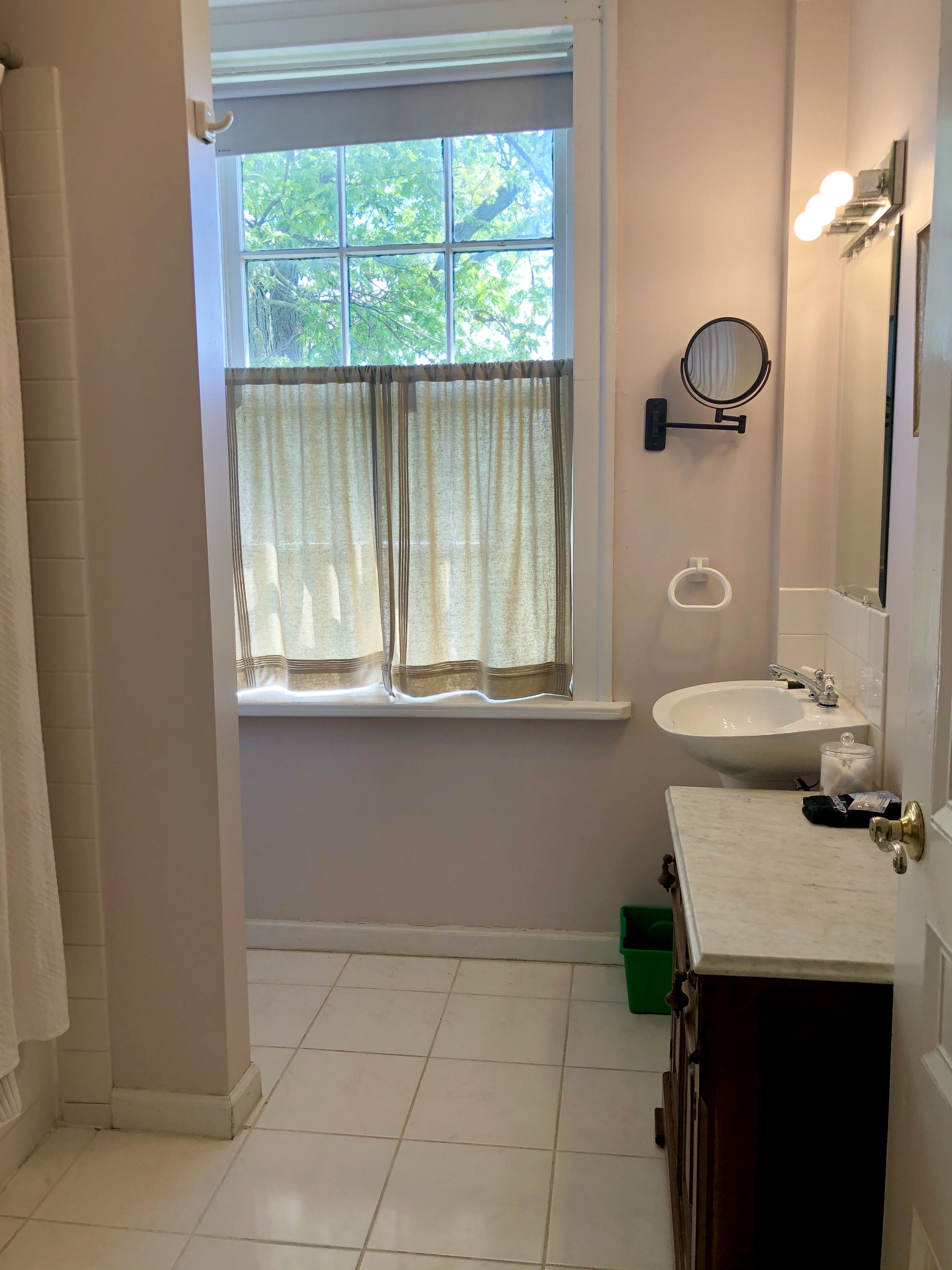 A bathroom with a window, a sink, a mirror, and a toilet.