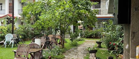 Un patio couvert aménagé avec du mobilier d’extérieur, un petit jardin et une vue sur les bâtiments voisins.