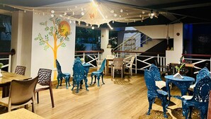 Un restaurante con suelo de madera, sillas azules, un mural de un árbol y una escalera.