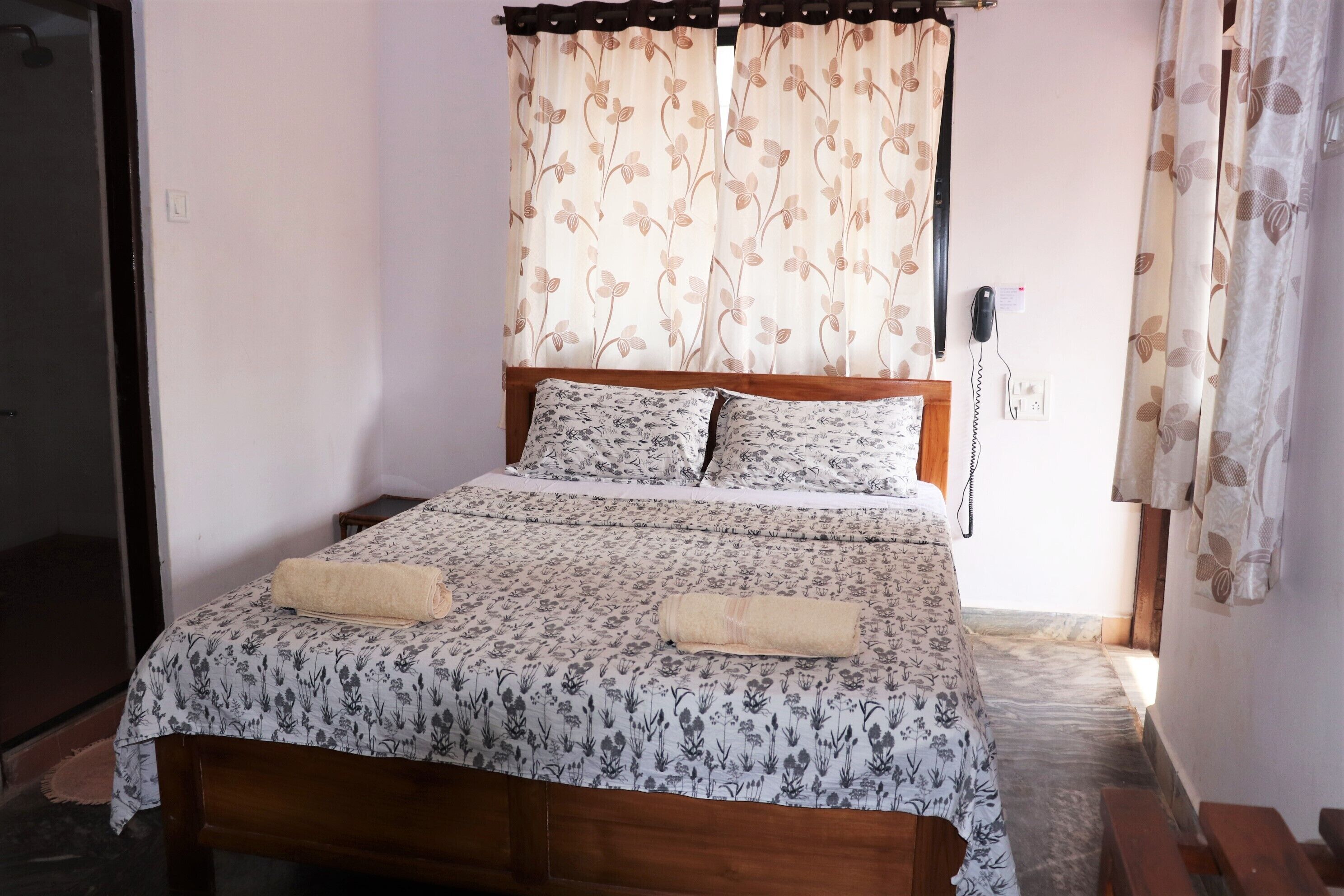 A bed with floral bedding, a wooden headboard, and two rolled towels.